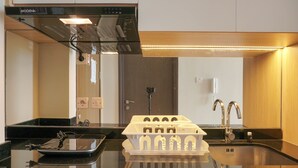Una cocina moderna con encimera negra, estufa integrada y un lavamanos con grifo.