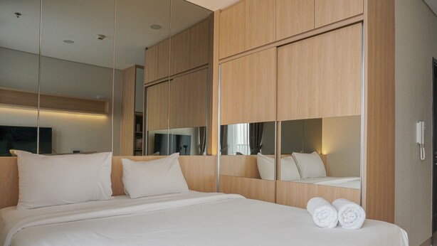 Una habitación de hotel moderna con una cama grande, un armario de madera y un espejo que refleja la habitación.