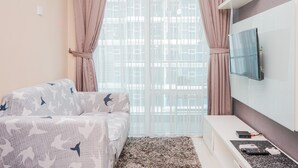 A modern hotel room with a bed, a TV mounted on the wall, and a window with curtains. - Great Choice 1BR at Brooklyn Alam Sutera Apartment (South Tangerang)