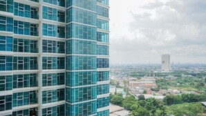 A high-rise building with a modern glass facade and multiple floors. - Great Choice 1BR at Brooklyn Alam Sutera Apartment (South Tangerang)