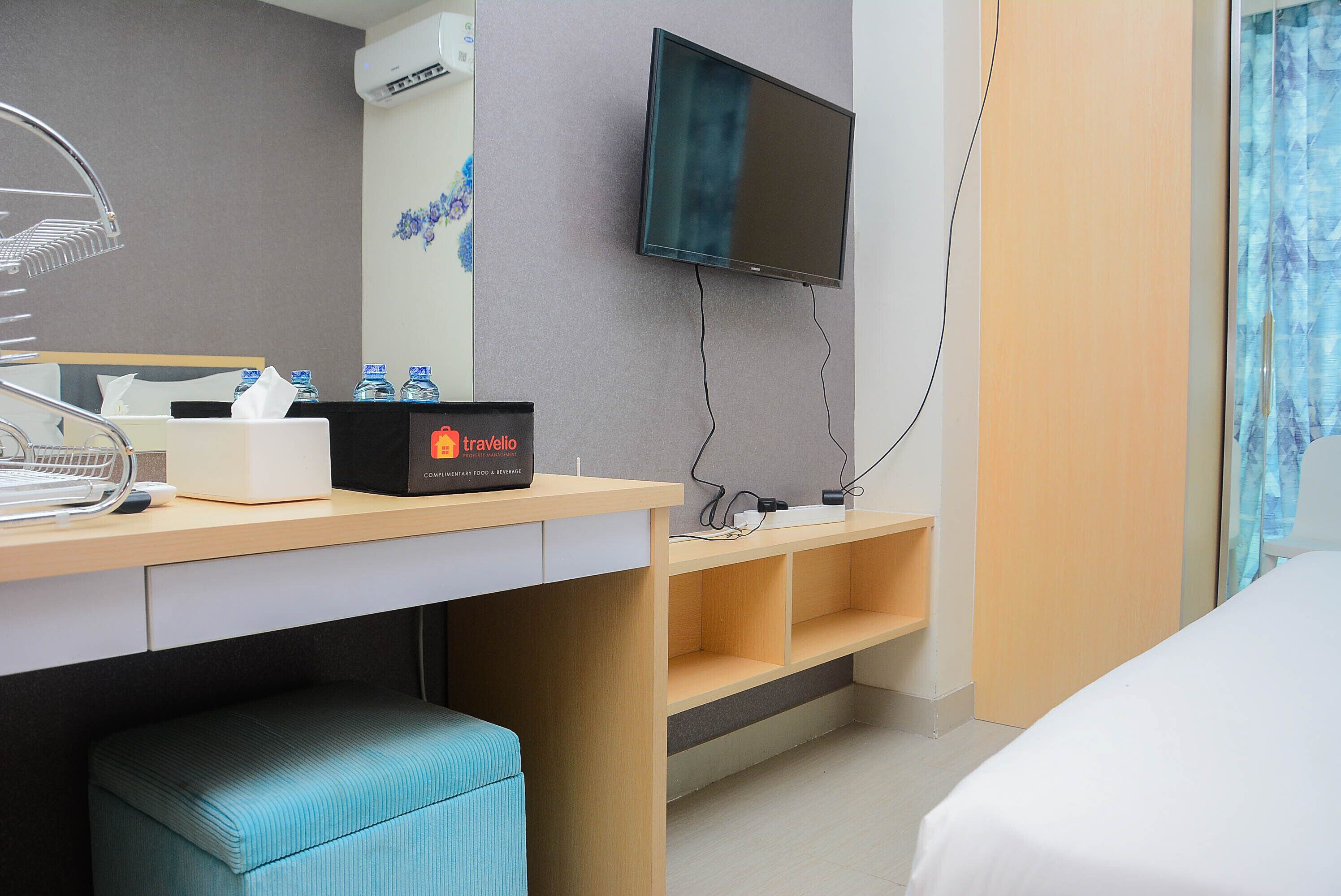 Habitación de hotel con cama, escritorio con computadora, televisión y baño con cortina de ducha.