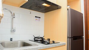 A kitchen with a stainless steel sink, a gas stove, and a refrigerator. - Cozy Stay 1BR at Grand Kamala Lagoon Apartment (Bekasi)