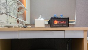 A hotel reception area with a metal dish rack, a tissue box, and a travelio branded box with water bottles. - Cozy Stay 1BR at Grand Kamala Lagoon Apartment (Bekasi)