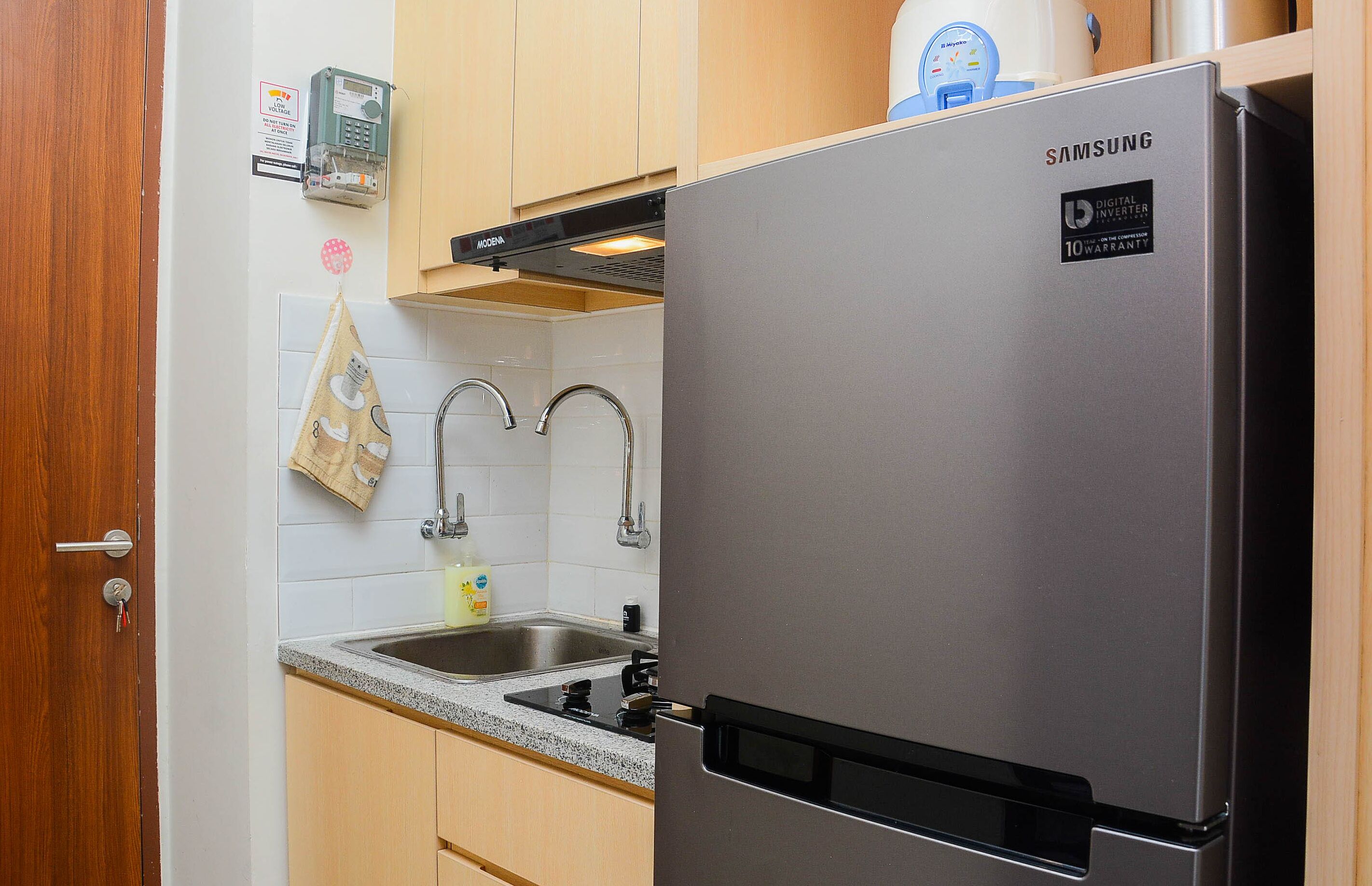 A kitchen with a stainless steel Samsung refrigerator, a double sink, and wooden cabinets.