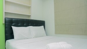 A neatly made bed with white linens and pillows, a folded white towel on the bed, and a black upholstered headboard. - Comfortable 2BR Bassura City Apartment near Bassura Mall (Jakarta)