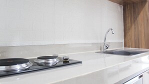 A kitchen with white subway tiles, a stainless steel sink, and a wooden countertop.