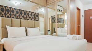 Un letto grande con lenzuola bianche, una testiera con motivo geometrico e una porta in legno.