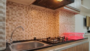 Una cucina con piastrelle a scacchi sul muro della cucina, un lavandino in acciaio inox, un fornello a gas e un espositore per piatti rosso.