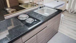 A modern kitchen with a black granite countertop, stainless steel sink, and a built-in stove. - Modern Classic Studio Room Bintaro Icon Apartment (South Tangerang)