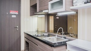 A modern kitchen with a stainless steel sink, a microwave, and a built-in oven. - Modern Classic Studio Room Bintaro Icon Apartment (South Tangerang)