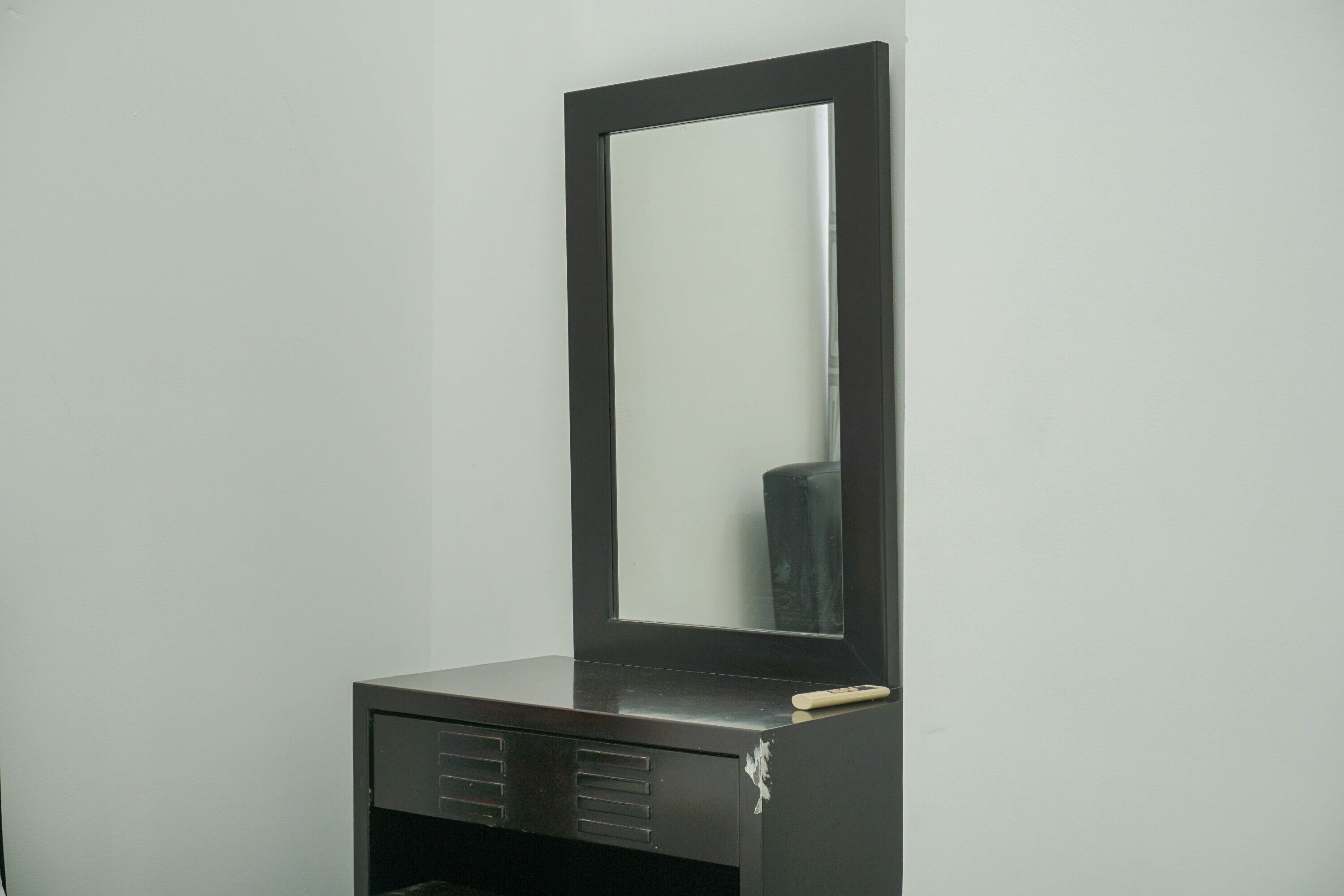 A black cabinet with a mirror and a remote control on top.