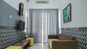 A living room with a sofa, a small table, a TV, and patterned wallpaper.