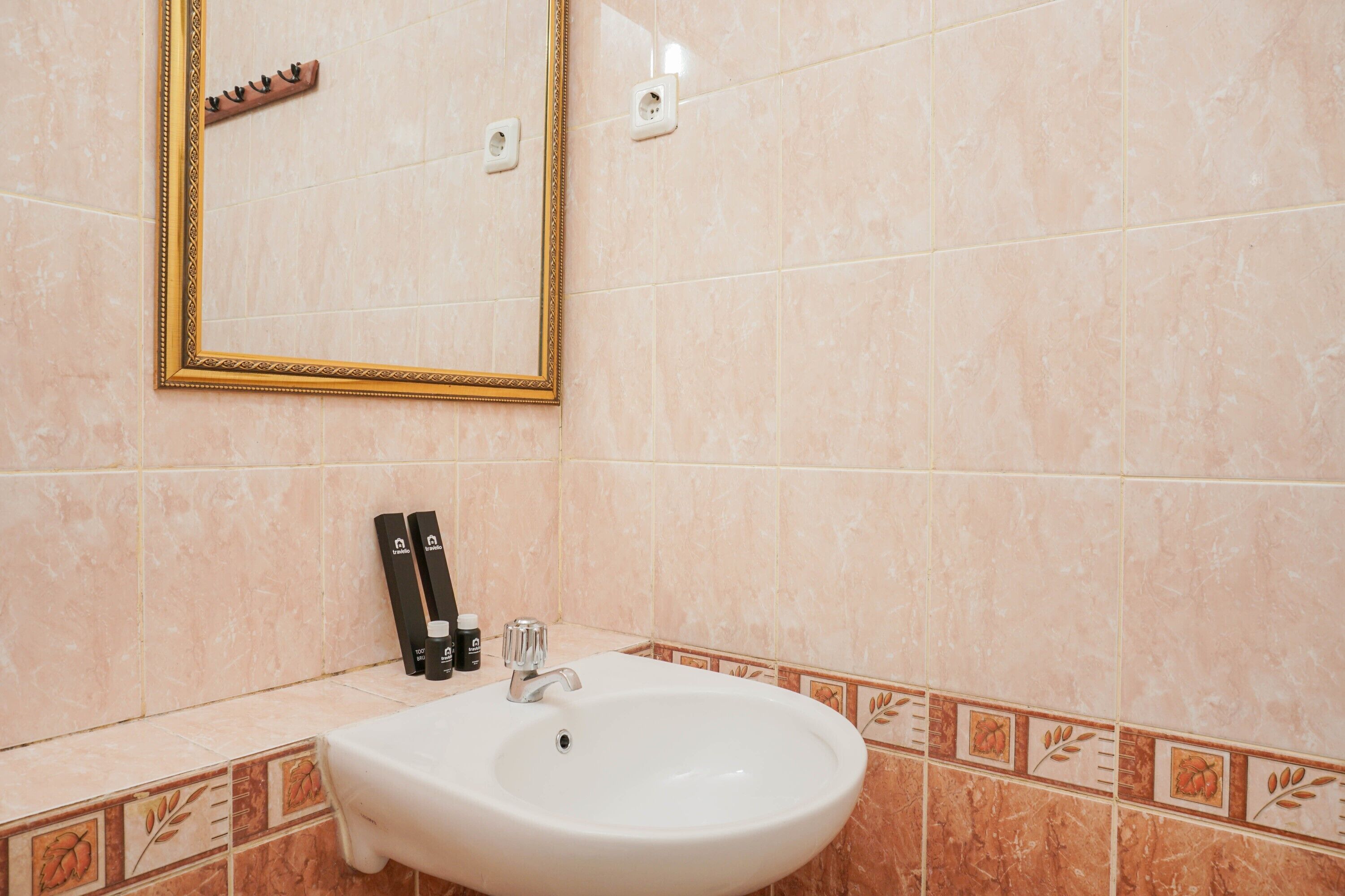 A bathroom with a white sink, a mirror with a gold frame, and toiletries on the counter.