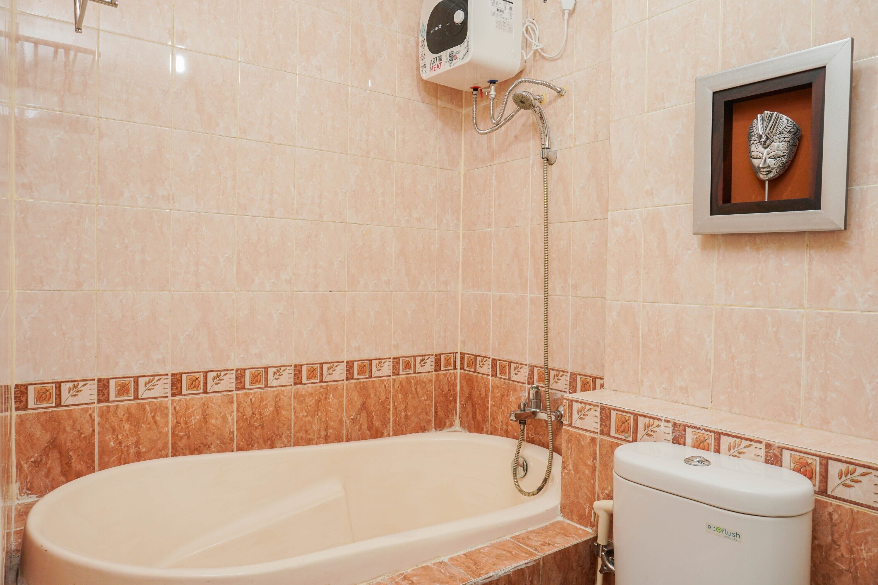 A bathroom with a bathtub, a showerhead, and a toilet.