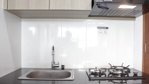 Una cocina con un lavamanos de acero inoxidable, una estufa a gas y un armario sobre el lavamanos.