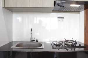 Uma cozinha com uma pia de aço inoxidável, um fogão a gás e um armário sobre a pia.