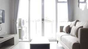 Una sala de estar moderna con un sofá, una mesa de centro y un televisor sobre un mueble.
