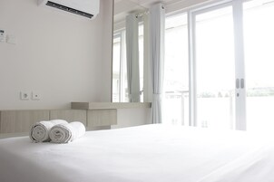 Una habitación de hotel con una cama grande, cabecera de madera, ventana con cortinas y vistas a la ciudad.