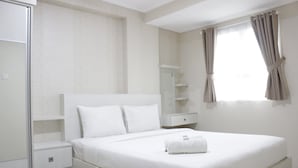 A bedroom with a bed, nightstands, a wardrobe, and a window with curtains.