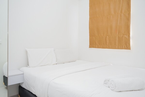 Experience comfort in this serene hotel room with a neatly made bed, wooden headboard, and a functional nightstand.