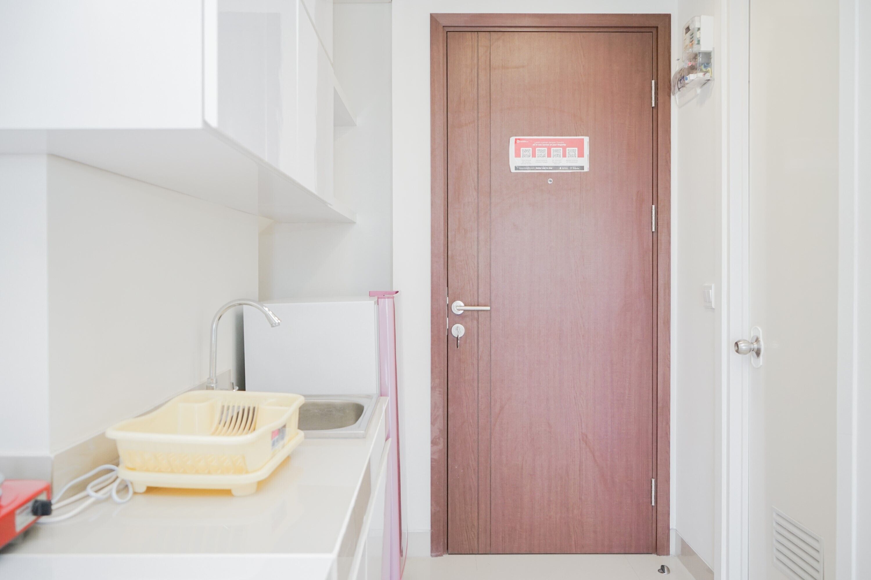 Une petite cuisine équipée d’un évier, d’une porte en bois et d’un plan de travail blanc.