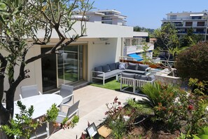 A modern outdoor living area with a pool, lounge chairs, and a dining table. - Rooftop Croisette/alexandre III (CANNES)