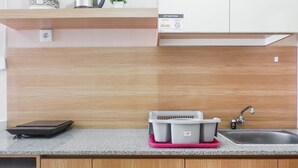 A kitchen with a granite countertop, wooden cabinets, a sink, and a dish rack.