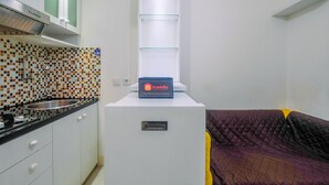 A compact kitchen with a tiled backsplash, a built-in stove, and a small refrigerator with a 'Travelio' sign.