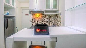 A modern kitchen with white cabinets, a tiled backsplash, and a travelio branded box on the counter.