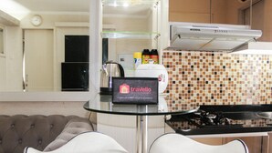 A kitchen with a glass table, two white chairs, a stove, and a Modena range hood. - Comfort 2BR Bassura City Apartment near Shopping Center (Jakarta)