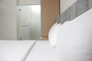 A modern hotel room with a large bed, a wooden wardrobe, and a glass door leading to a bathroom. - Deluxe & Cozy 3BR at Gateway Pasteur Apartment (Cimahi)