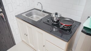 Une cuisine équipée d’un évier à deux bacs, d’une cuisinière et d’une poêle.