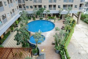 Guests can enjoy a refreshing swim in the central courtyard pool surrounded by balconies and lush greenery.