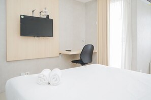 Relax in a serene space with a comfortable bed, flat-screen TV, and office chair.