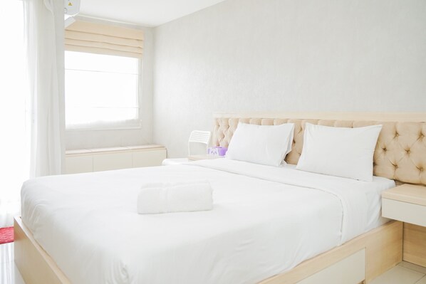 Relax in a spacious room with a large bed, bedside table, and window with a blind.