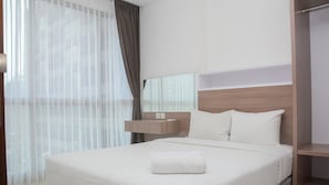 Ein modernes Hotelzimmer mit einem ordentlich bezogenen Bett, einem Nachttisch und einem großen Fenster mit durchsichtigen Vorhängen.