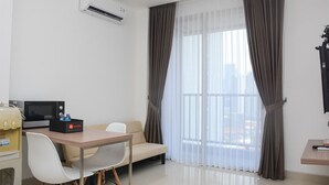 Ein modernes Hotelzimmer mit Essbereich, einer Couch, einem Fernseher und einer Klimaanlage.