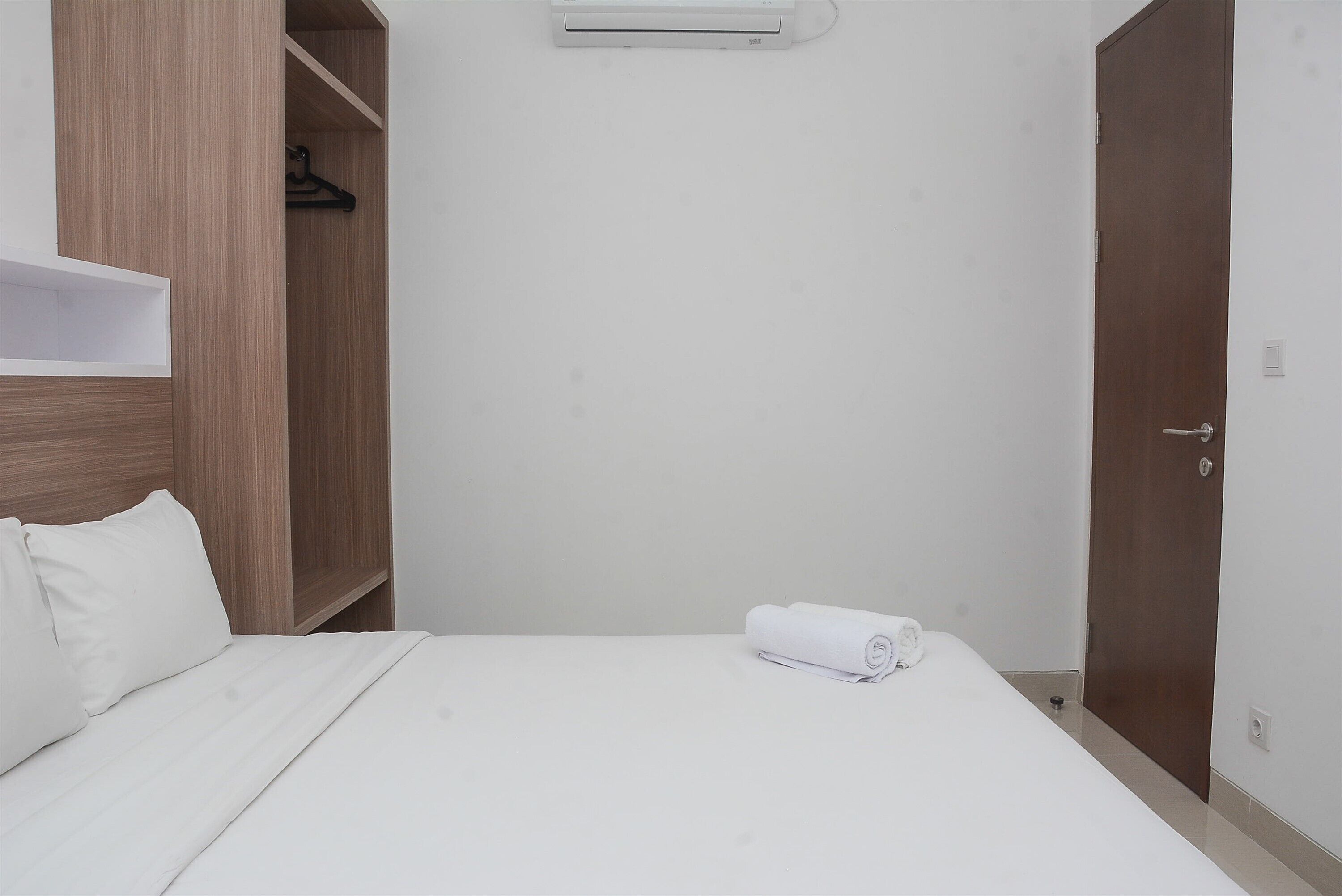 Una habitación de hotel con una cama, un armario de madera y una puerta.