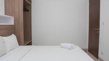 Una habitación de hotel con una cama, un armario de madera y una puerta.