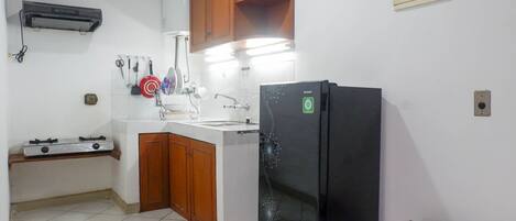 A compact kitchen with a gas stove, sink, and black refrigerator.