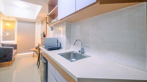 Una cocina moderna con encimeras blancas, pileta de acero inoxidable y muebles de madera.