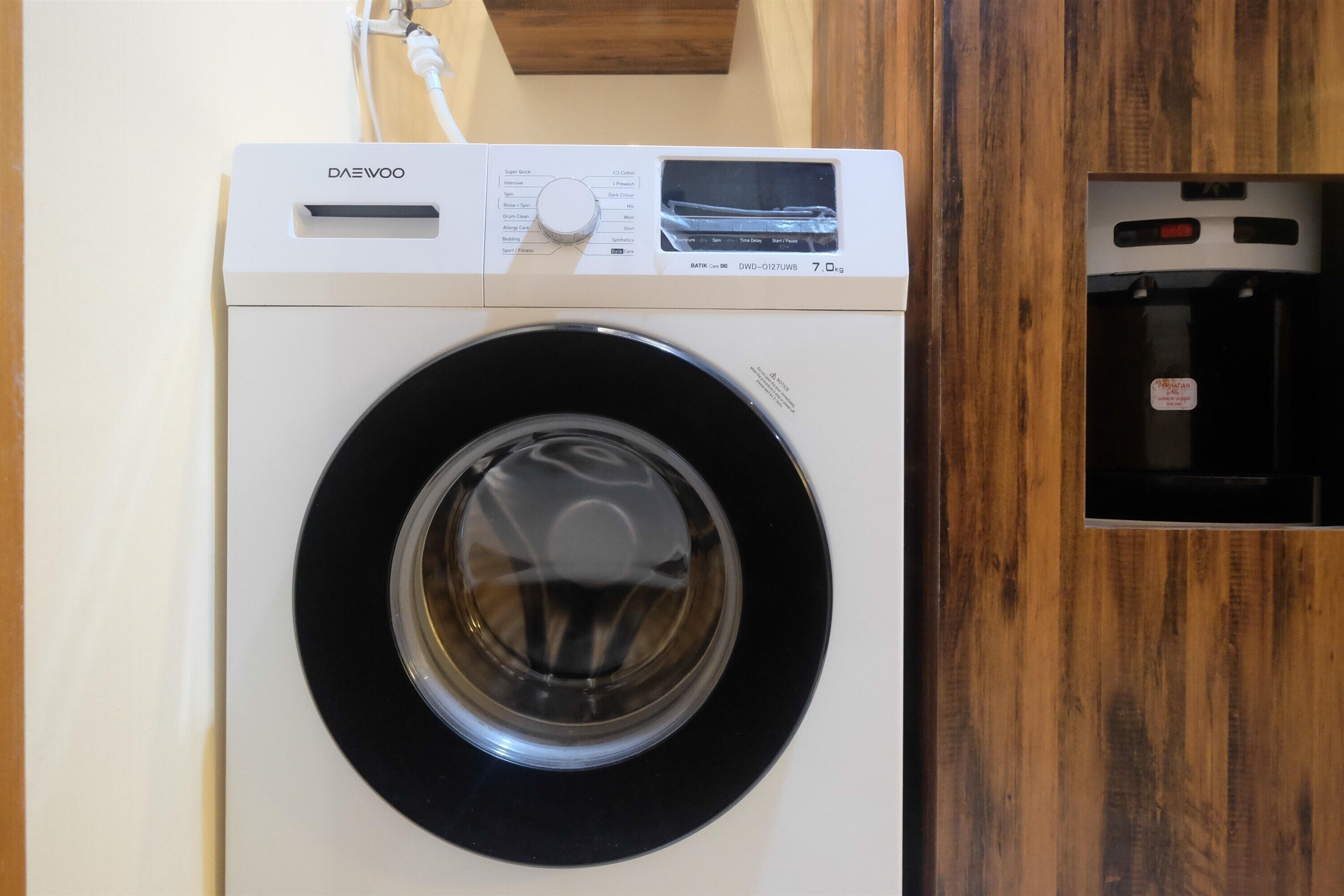 A front view of a front-loading washing machine with a control panel and a water inlet.