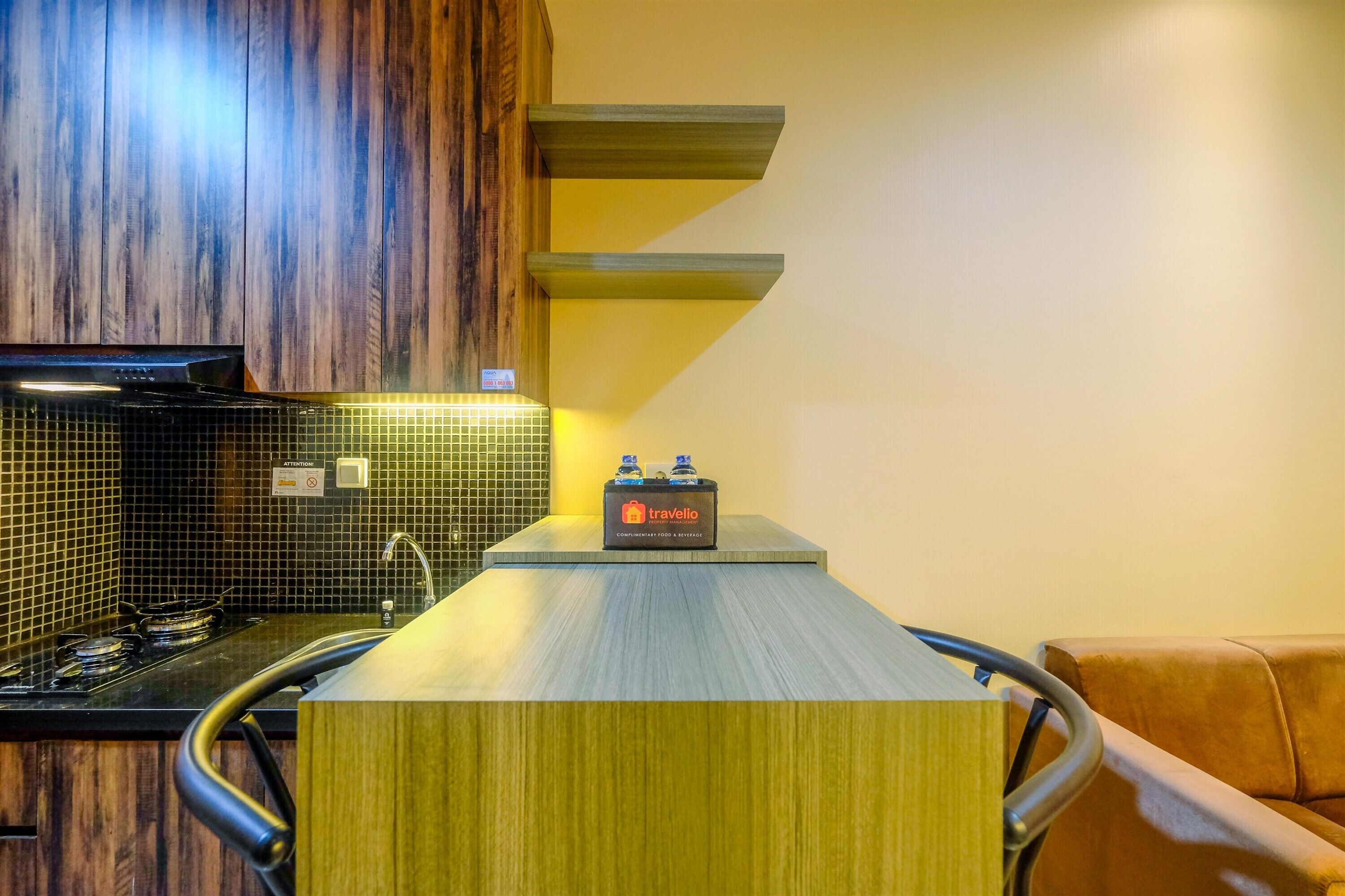 A modern kitchen with a wooden backsplash, a gas stove, and a travel station with a bottle of water.
