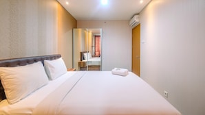 Hotellihuone, jossa on suuri sänky, sängynpääty, yöpöytä ja peili.
