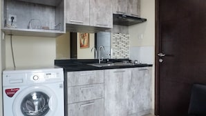 Une cuisine compacte équipée d’un lave-linge, d’un évier et d’un crédence carrelée.