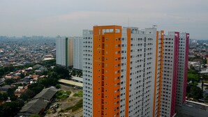 A high-rise building with multiple floors, featuring a prominent orange section and a pink section. - Comfort Studio at Green Pramuka Apartment near Shopping Center (Jakarta)