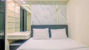 Hotellihuone, jossa on sänky, kaksi valkoista tyynyä, marmoriseinä ja lasihyllykkö.