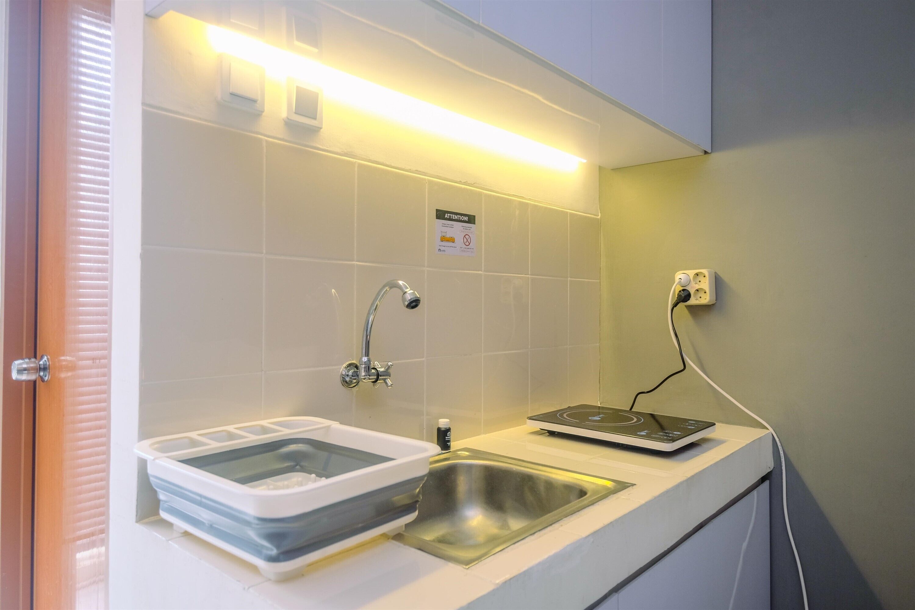 A bathroom with a sink, a faucet, a soap dispenser, and a power outlet.