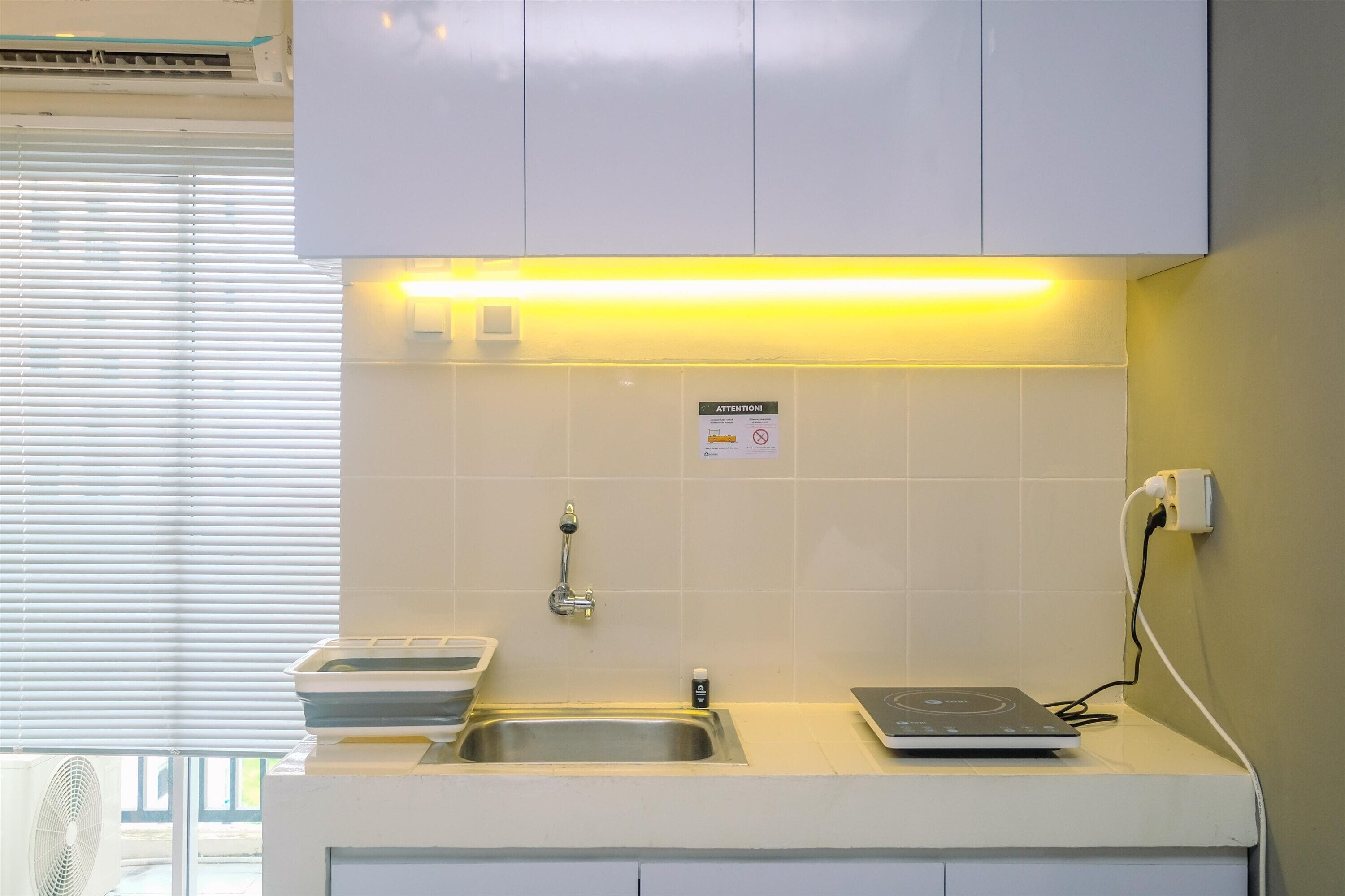 A modern kitchen with a built-in sink, a small countertop, and a wall-mounted fan.