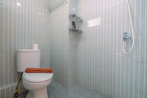 A bathroom with a toilet, a shower, and a towel rack. - Best and Simply Homey Studio Cinere Resort Apartment (Depok)